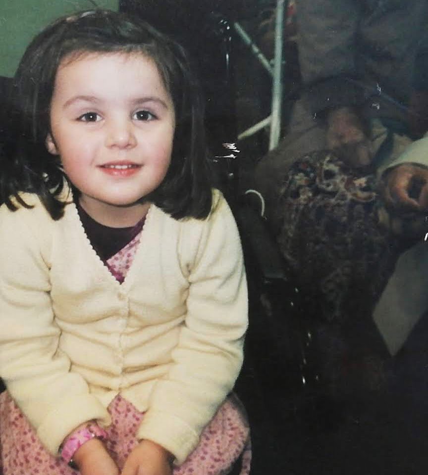 Little girl looking at the camera wearing a cardigan