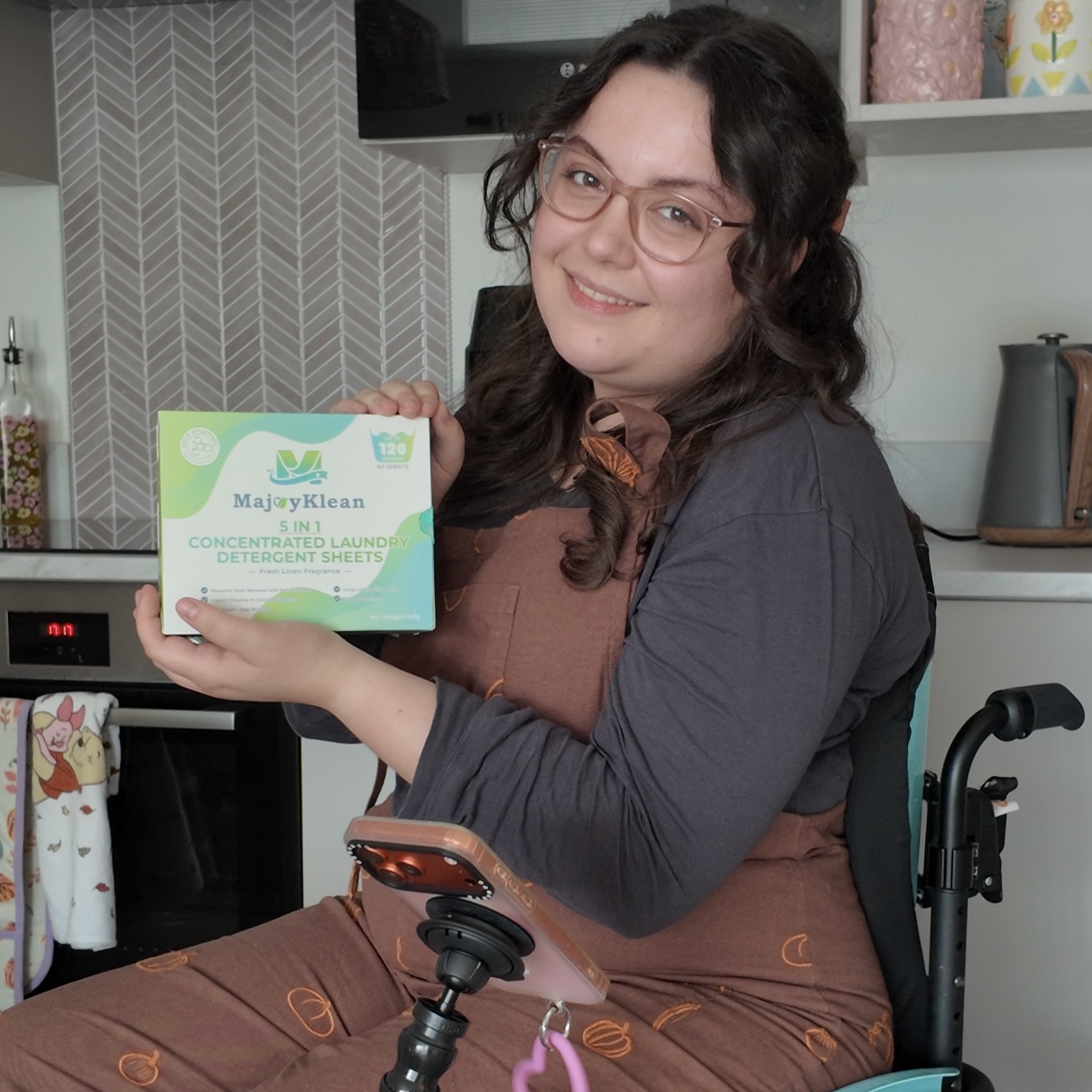White woman with brown hair, sitting in a wheelchair wearing dungerees