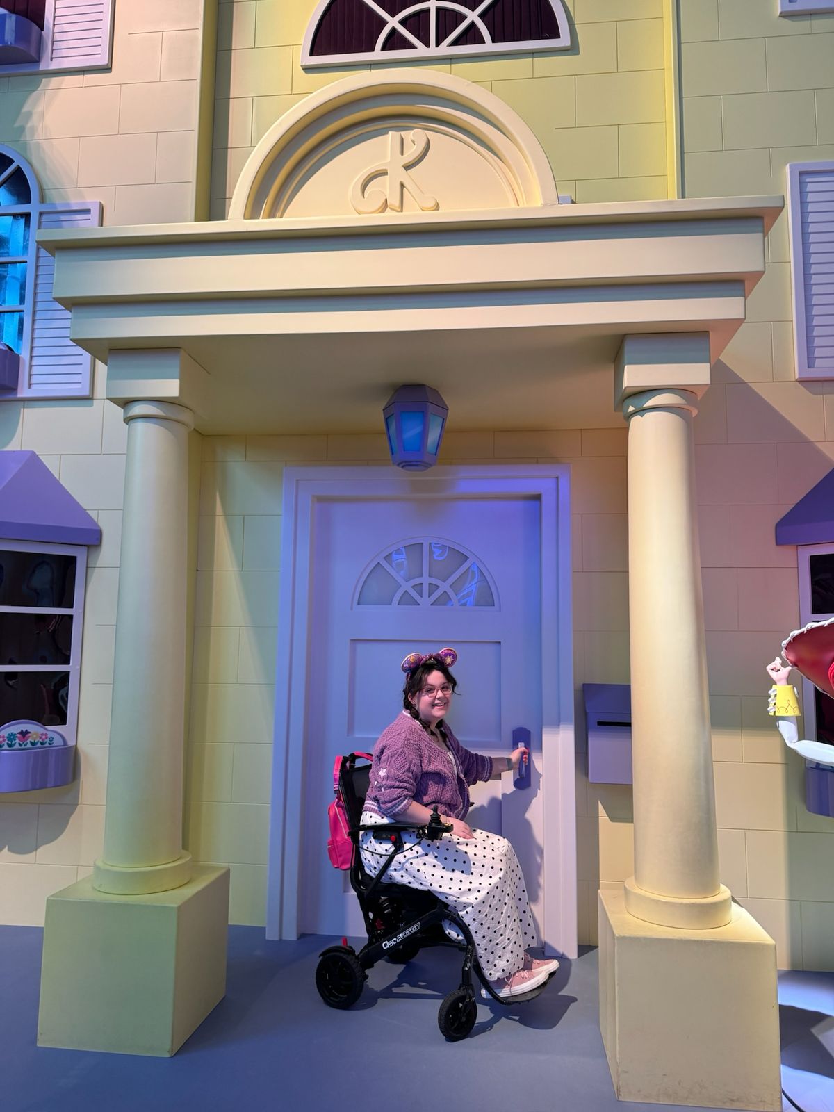 Imali Chislett in her wheelchair by a doorway, smiling.