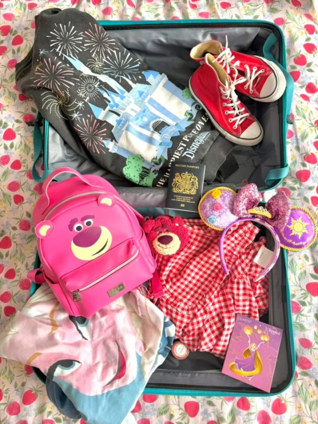 When you suitcase starts looking like this, you know it's nearly time to visit the mouse 👀As we all know, I suck at travelling light so I can confirm a lot more was added to the case before the trip but we're not going to talk about that!VD:
1: A flatlay of my suitcase open on my bed, with various Disney themed items inside, including a Lotso bear pink backpack, a black jumper with the Disney Castle on it, Red converse, makeup, an Elsa skirt and my passport.
2: A close up of some of the items, including my Lotso bag and keyring, a red gingham top and the Elsa skirt.
3: A close up of some more of the items, including the red gingham top, an eyeshadow palette with Rapunzel on it and my purple princess Mickey ears from my last visit (they're very sparkly!).