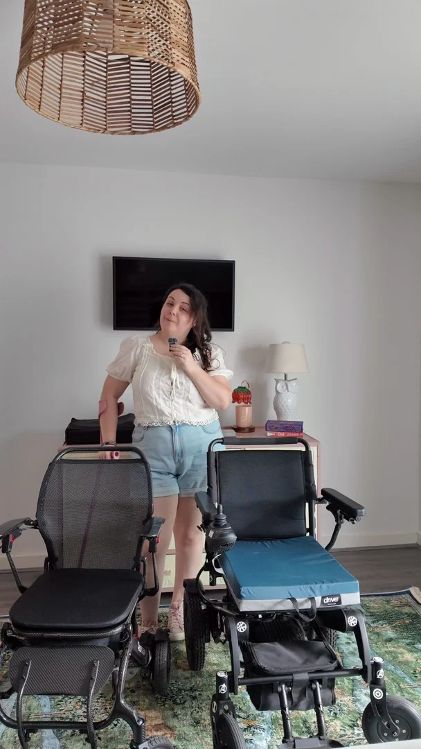 Episode 5 of The Wheel Deal: Everyday chair or just for occasions?VD: A white woman with brown hair, stood talking to you with two black powered wheelchairs nearby.