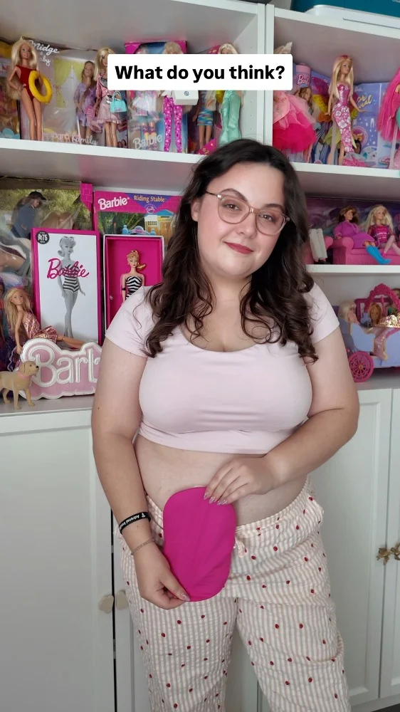 I've collected over 100+ Barbies throughout my life, but I've never seen one that reflects my experience of living with a stoma. This World Ostomy Day, I'm calling on Mattel to change that 💖VD: A wall of Barbies in Imali's flat. She keeps showing different dolls up close in their boxes and then at the end it cuts to her, stood in front of her Barbies with her stoma on show. She has a pink bag cover on and a light pink top.